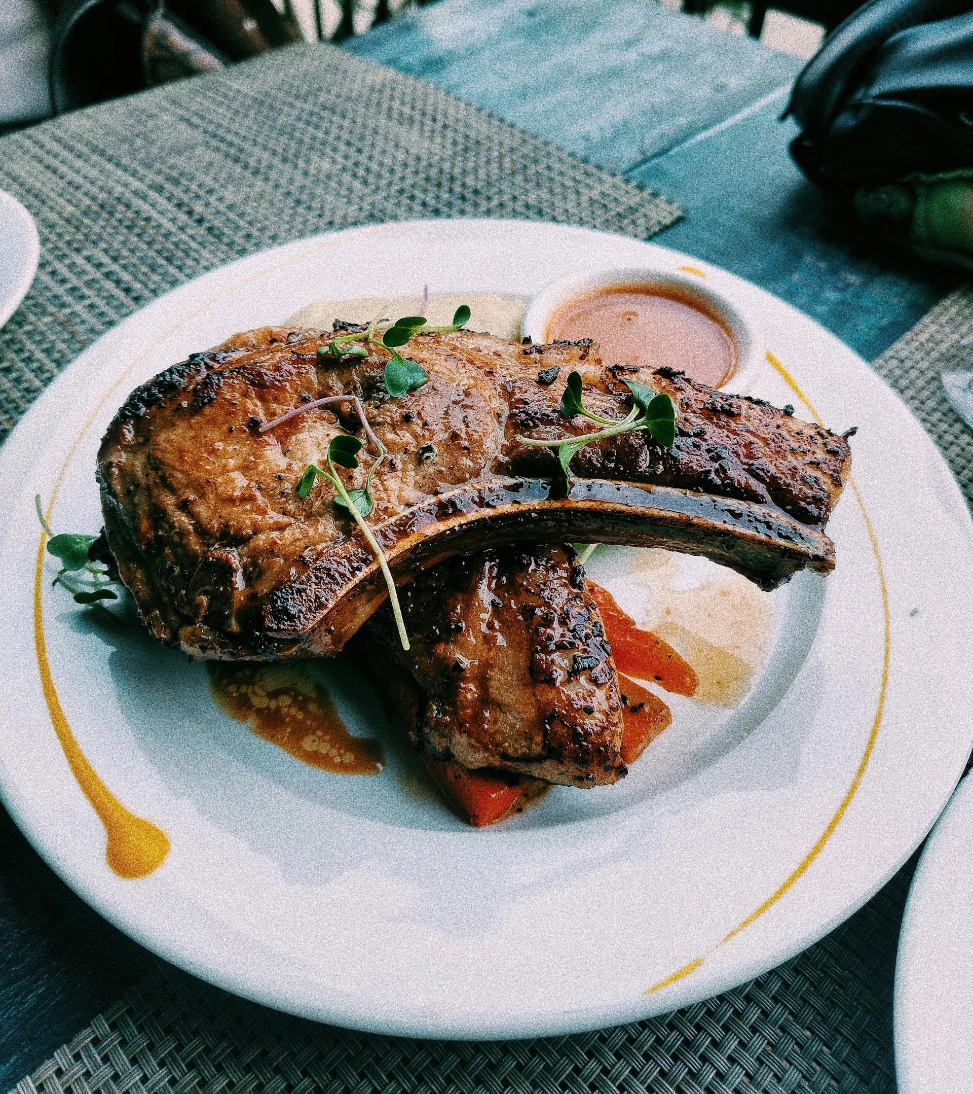 Golden brown air fryer pork chops on a white plate with roasted broccoli