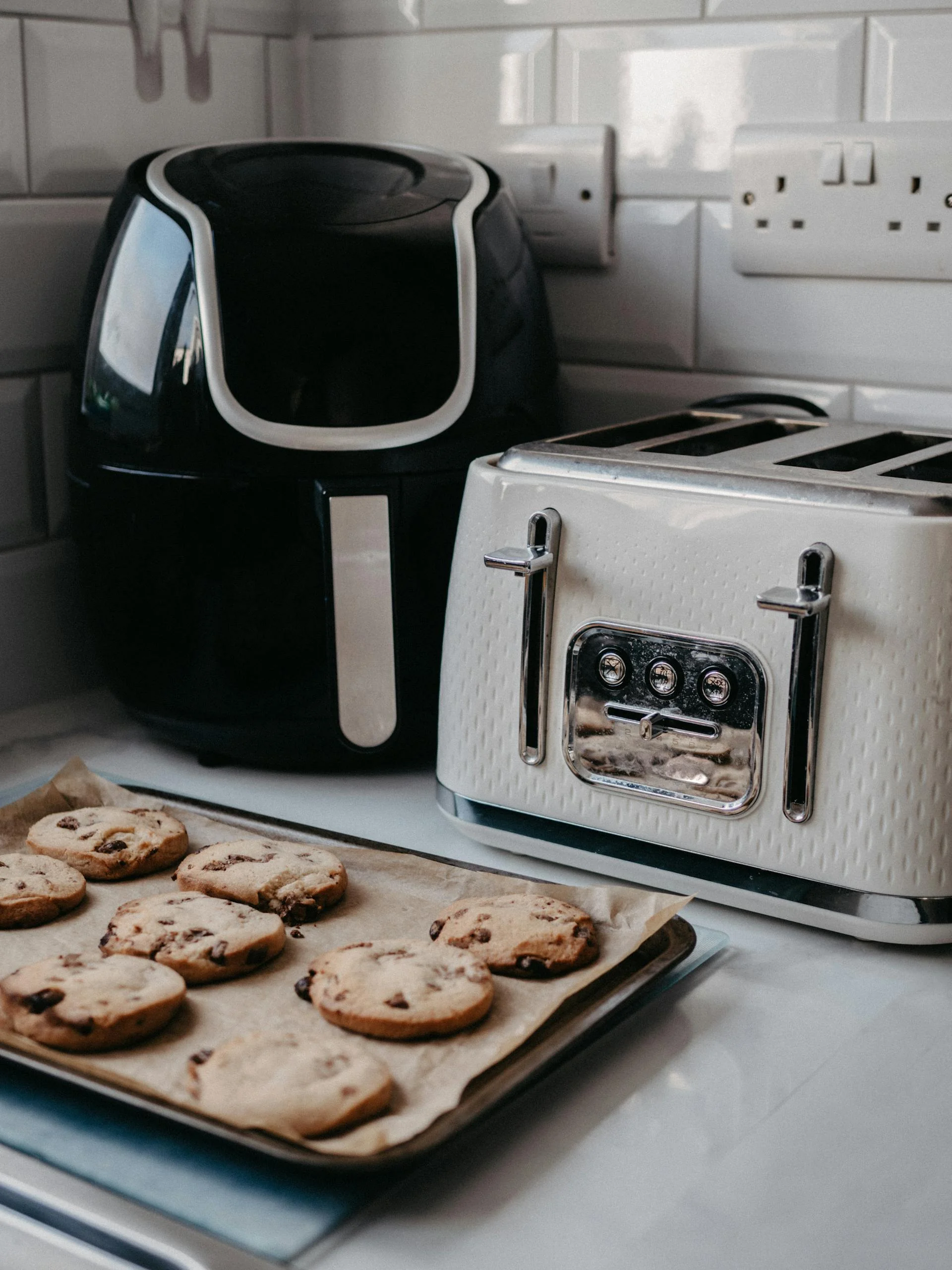 Three air fryers on a kitchen counter with test food results on plates
