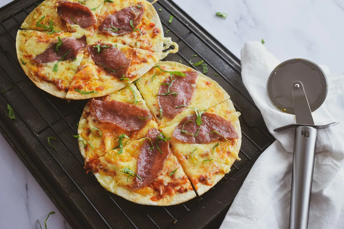 Two tortilla pizzas cooked in an air fryer basket