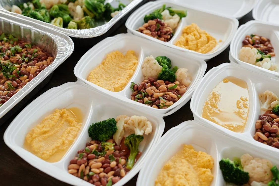Glass meal prep containers filled with rice, grilled chicken, and roasted vegetables on a kitchen counter
