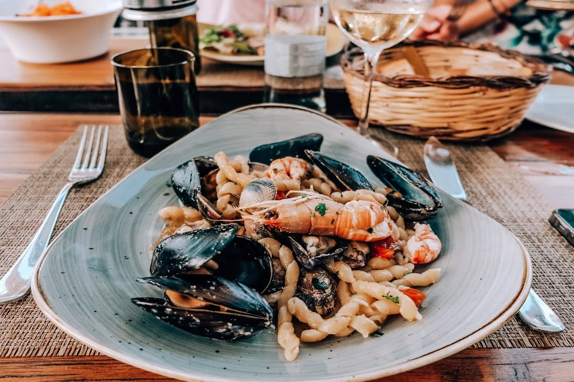 Garlic butter shrimp pasta in a white bowl with cherry tomatoes and fresh basil