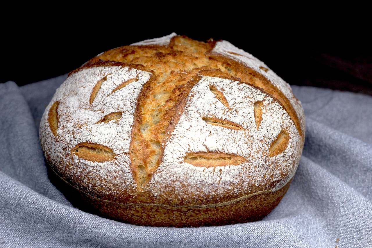 Sliced homemade sourdough bread loaf with open crumb on a wooden cutting board