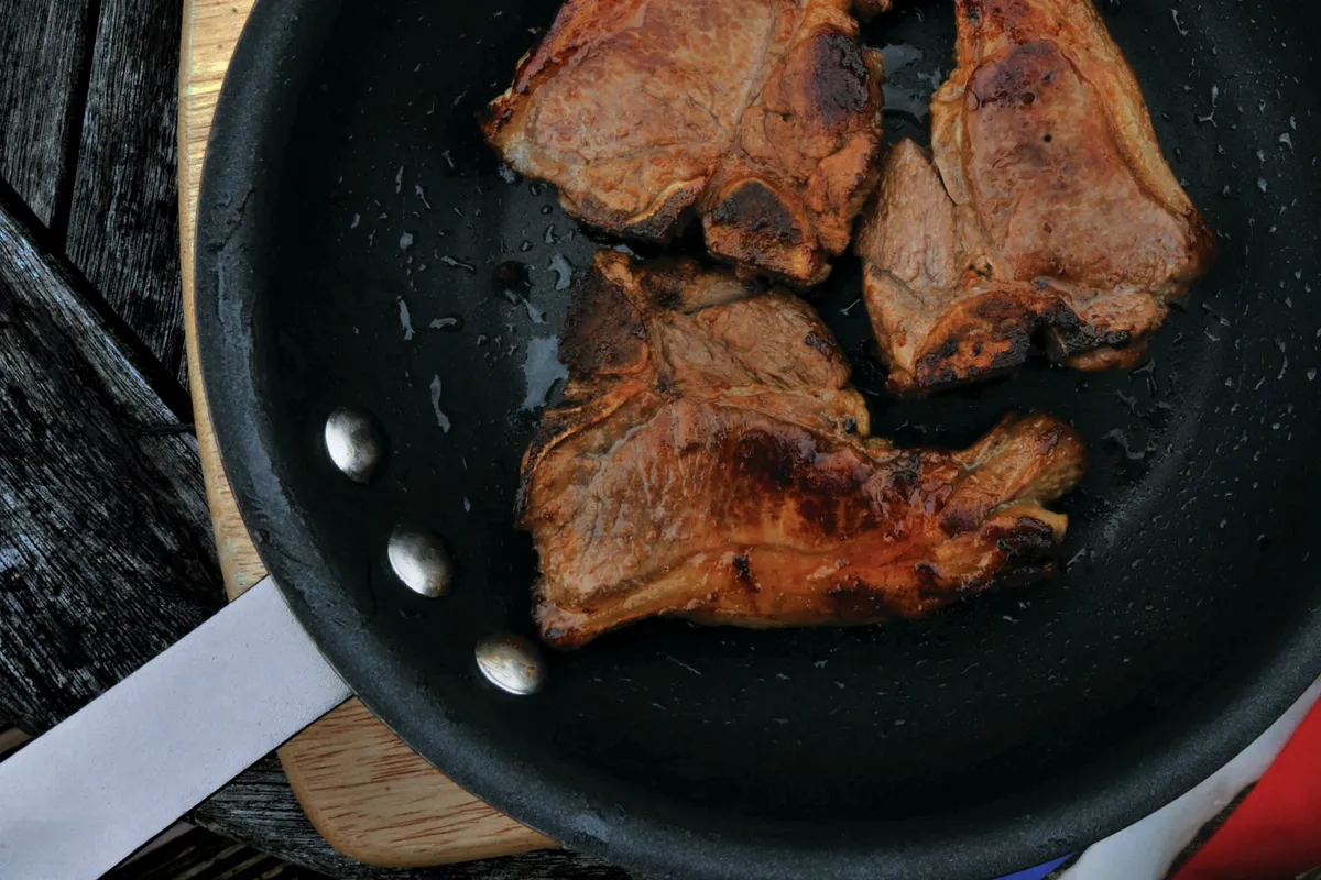 Three chops browning in a heavy skillet over high heat