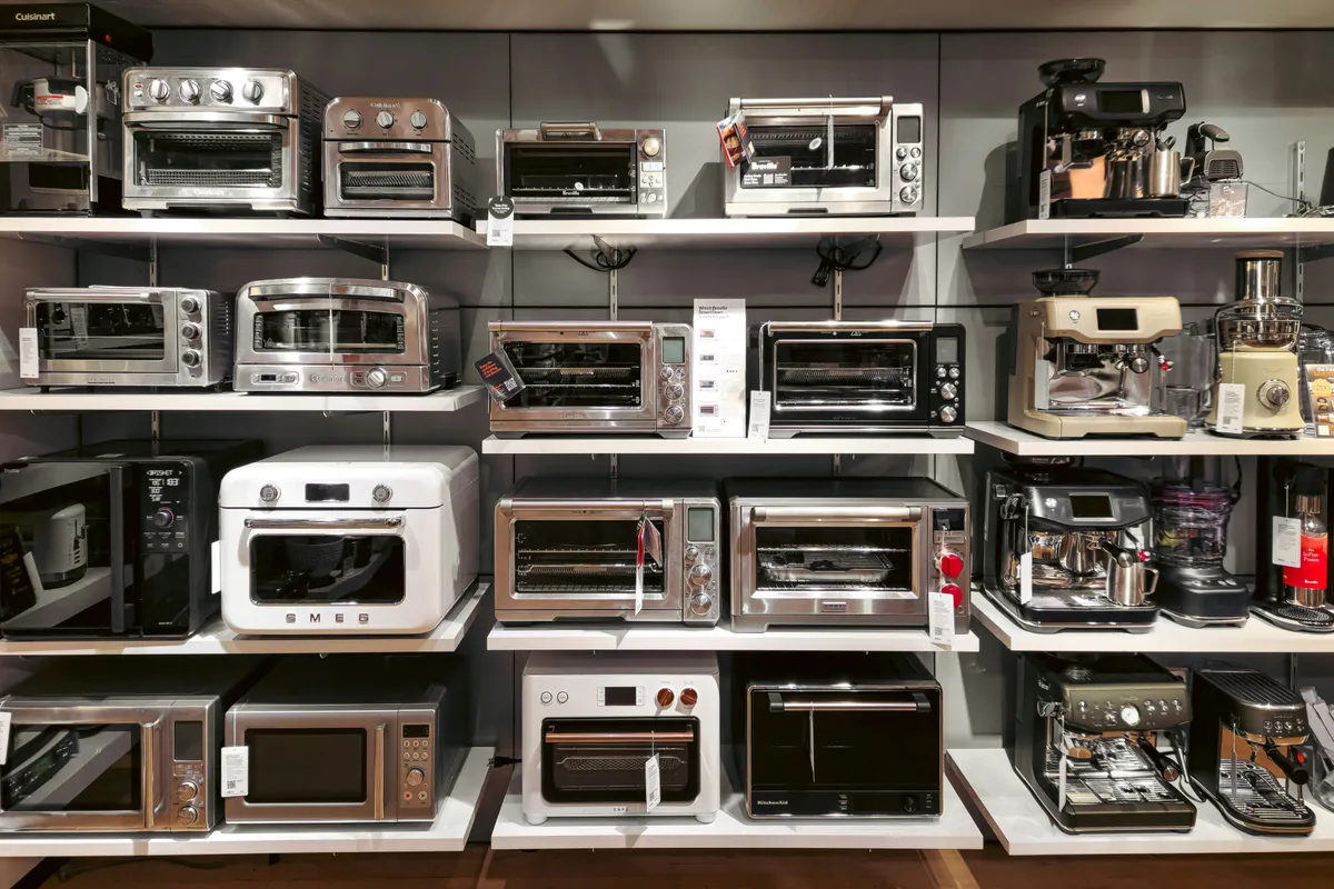 Countertop cookers lined up on a store shelf, price tags forward