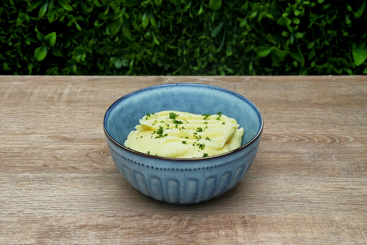 A rougher mash in a bowl on a bare wooden table