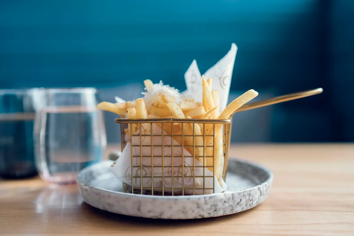 Freshly cooked fries piled in a metal fry basket