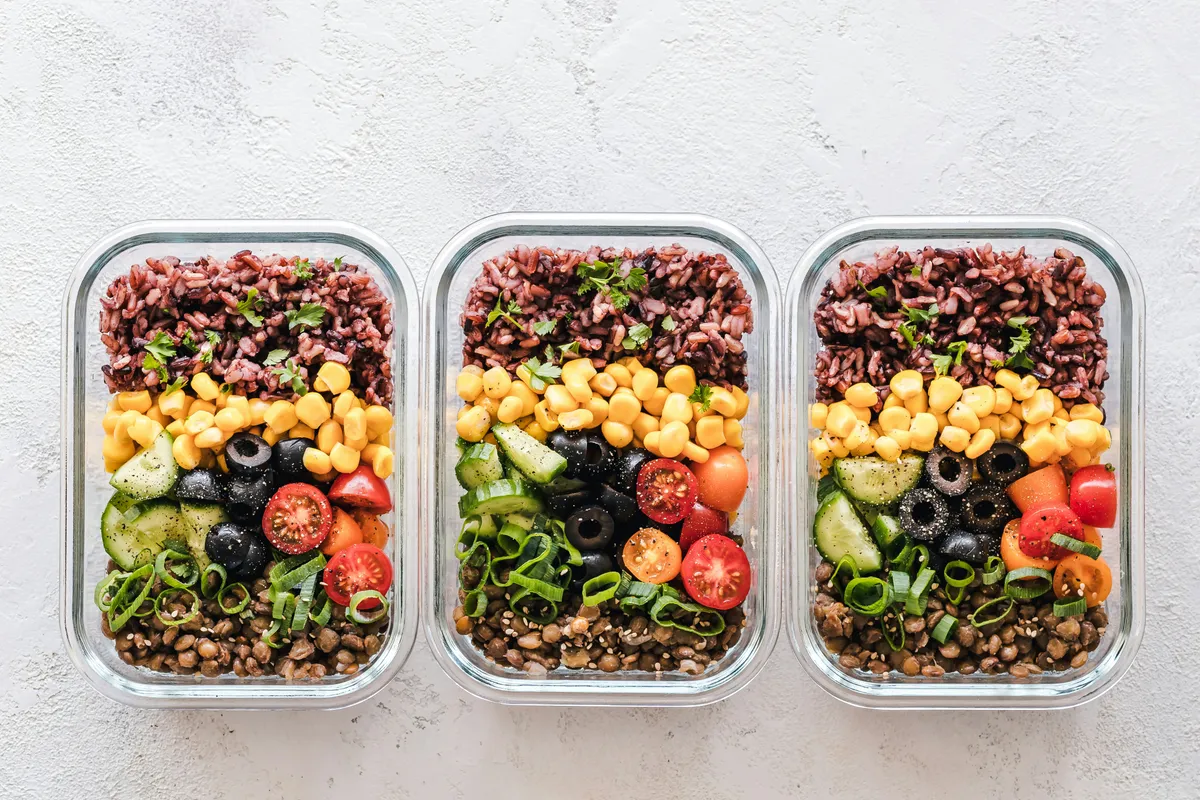 Three glass boxes packed with grains, beans and cut vegetables
