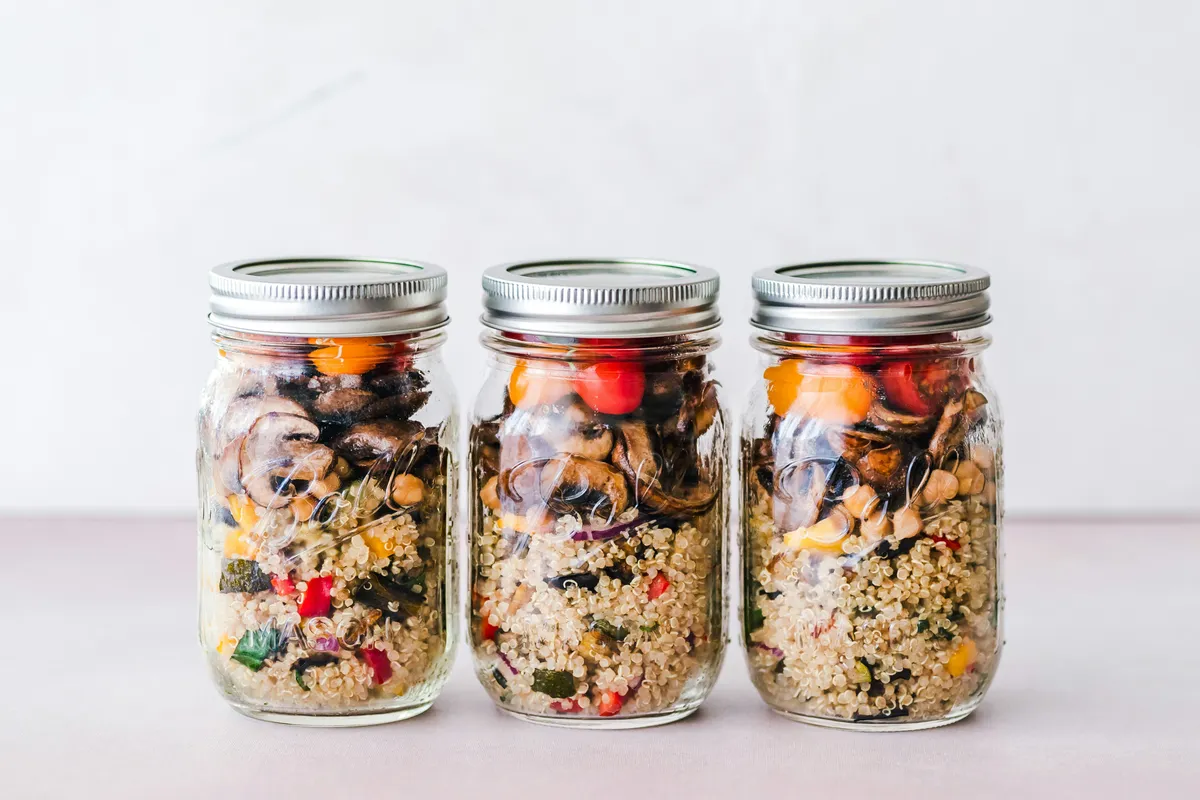 Three lidded jars holding a week of lunches on a pale surface