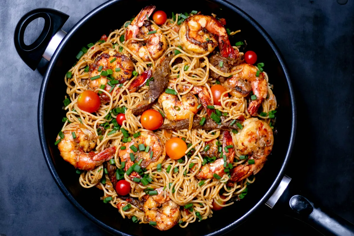 Pasta and shrimp finishing together in the pan with tomatoes