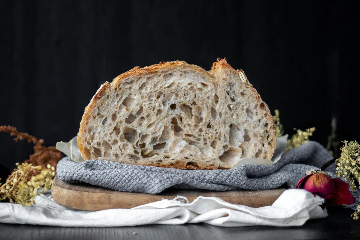 A finished sourdough loaf resting on folded kitchen cloth
