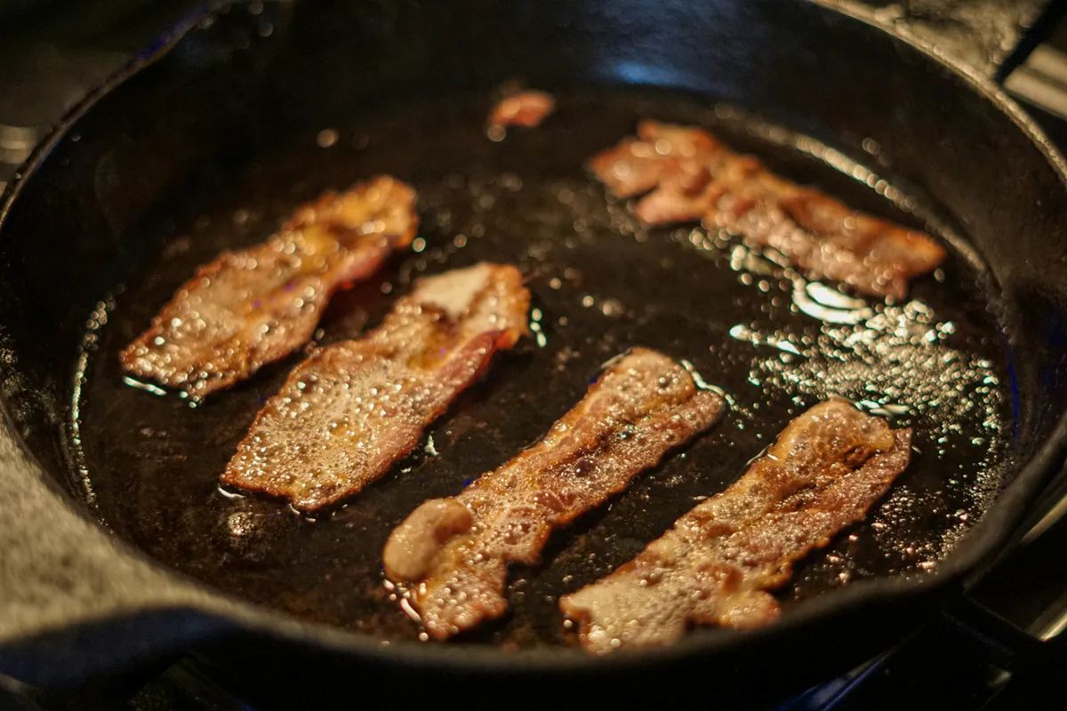 Bacon curling and spitting in a cast iron skillet