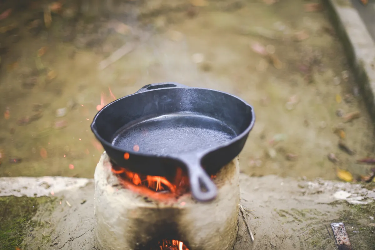 A cast iron pan sitting over open flame, the way seasoning sets