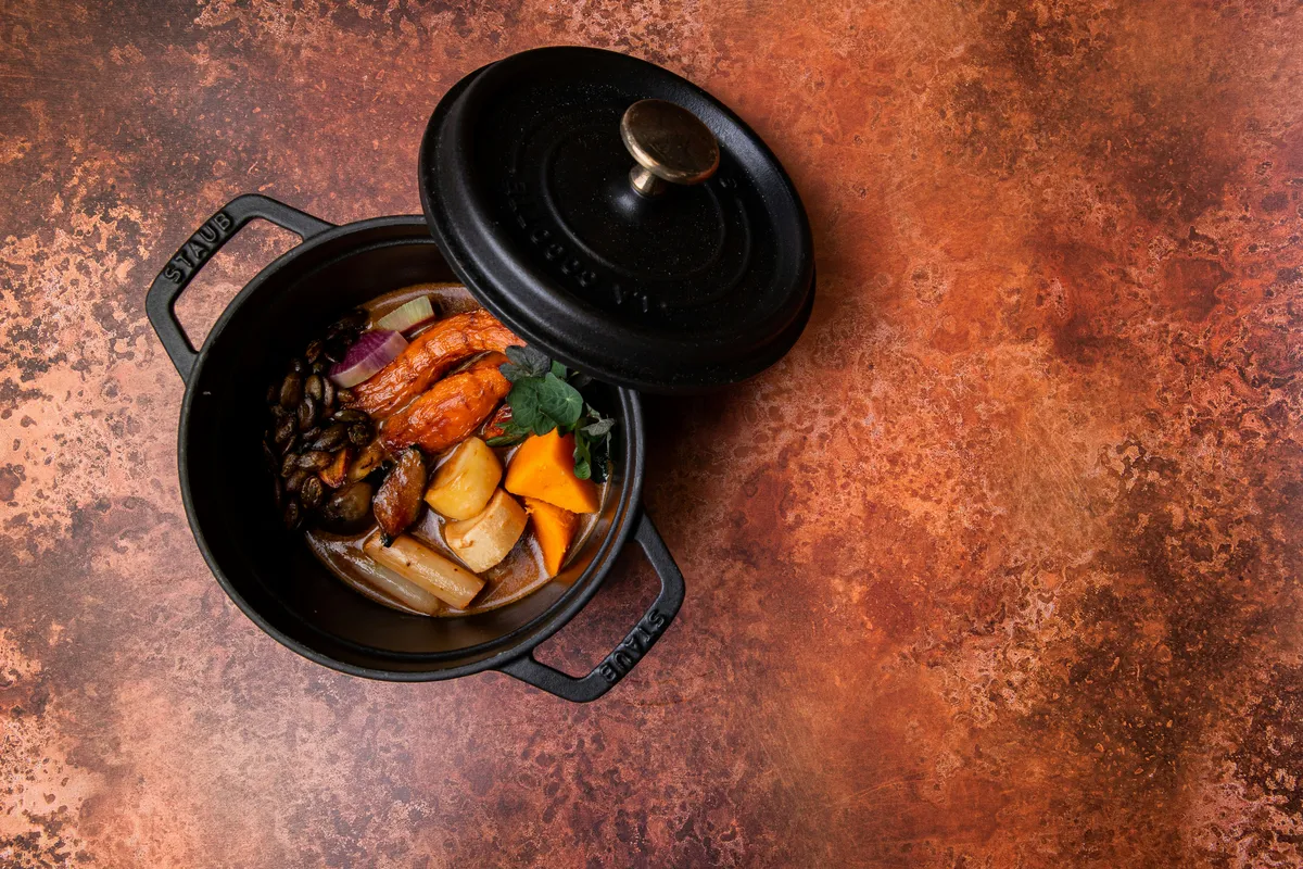 A black pot crowded with braised vegetables and sauce