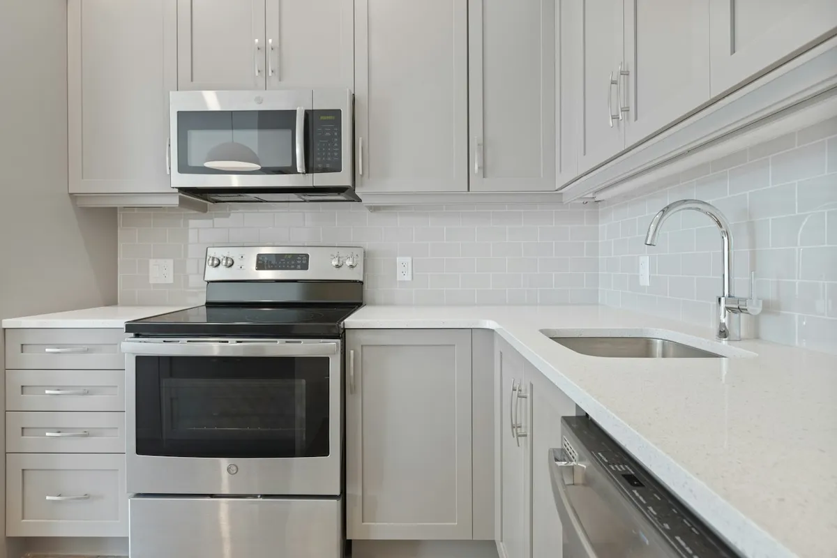 A white microwave oven sitting on a white wooden kitchen cabinet