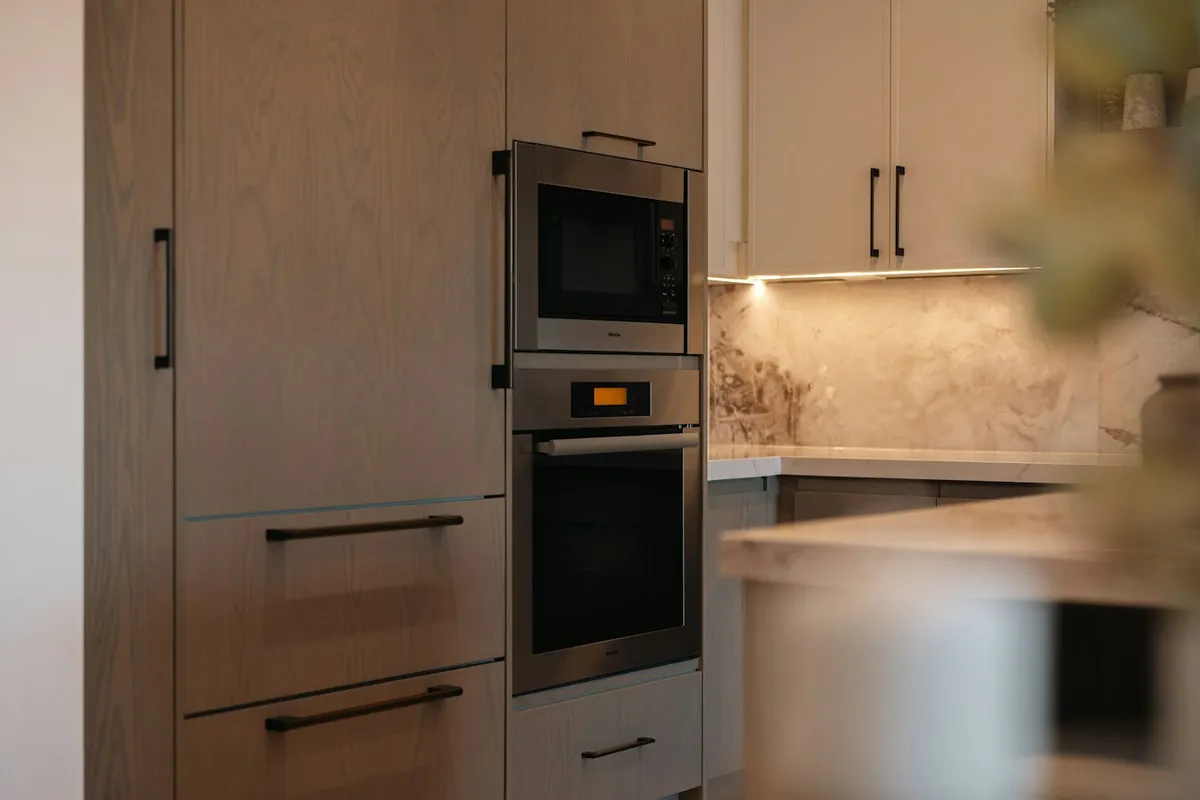 A modern kitchen with a built-in oven and microwave in a cabinet run