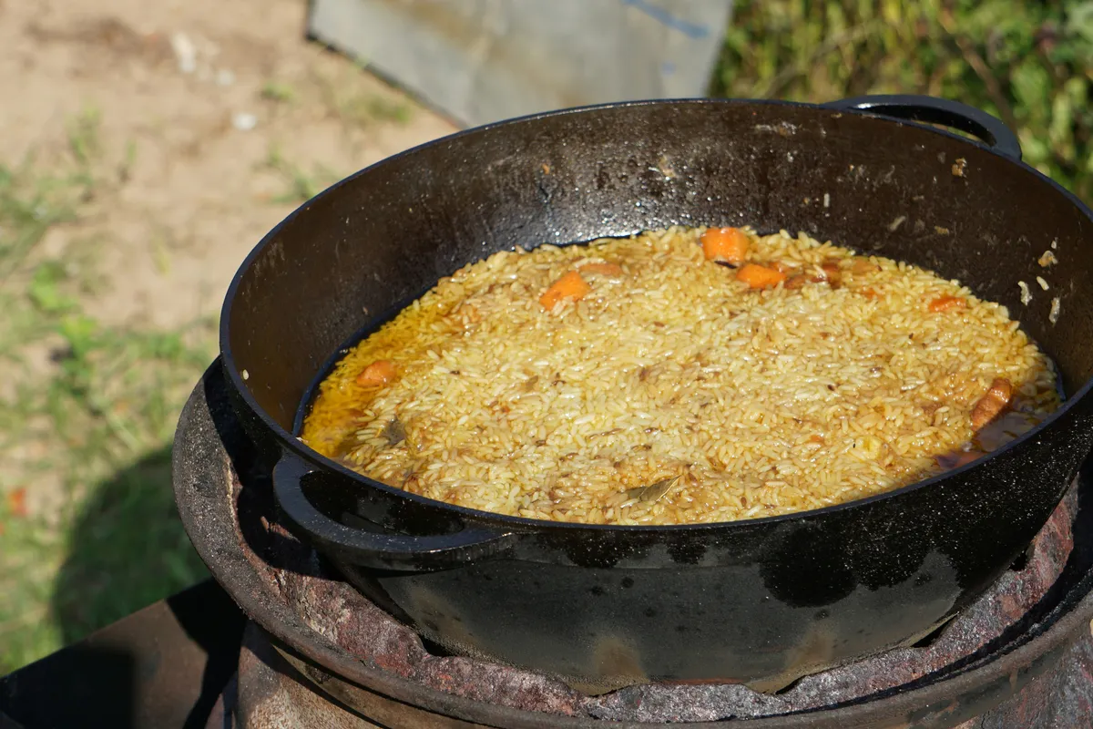 A covered pot simmering on the stove with the lid just lifted