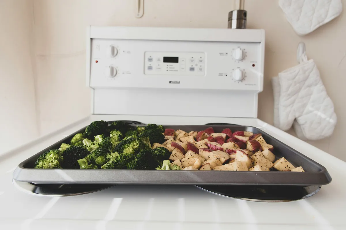 Seasoned broccoli and potatoes spread on a tray ready for roasting